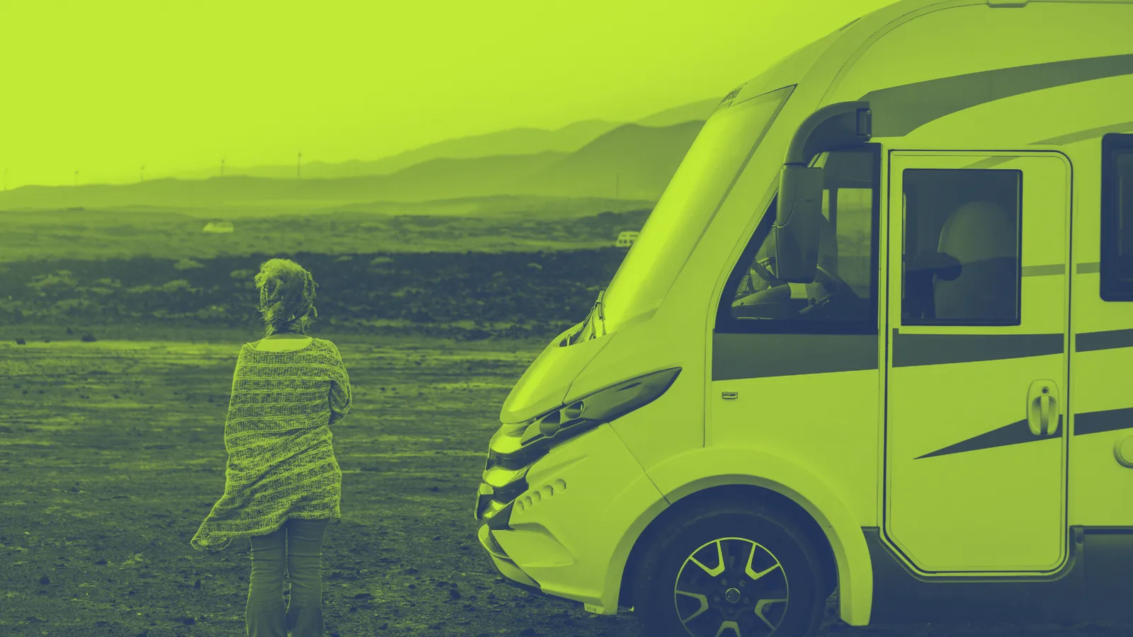 Frau steht in einer Vulkanlandschaft neben ihrem Wohnmobil – Wohnmobilversicherung ohne festen Wohnsitz